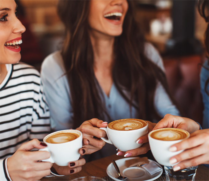 Women Laughing While Holding Coffee Cups