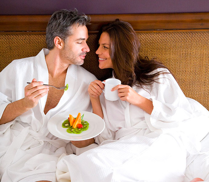 couple enjoying breakfast in hotel bed